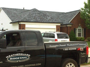 red brick house with grey roof and a black pickup truck in front of it