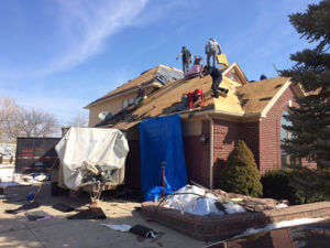 workers standing on a house roof adding shingles