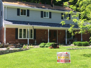 colonial style house getting new black shingles installed