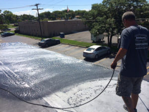 a man spraying a roof coating on top of a flat roof