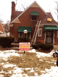 old red brick house with green awnings