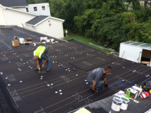 two male workers putting in new roof of building