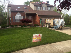 workers installing new roof on brick house