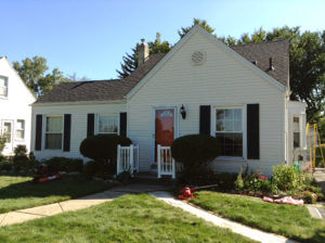 small yellow house with red door and black shingles