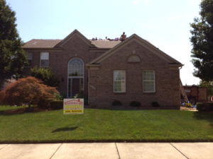 large brick house with men installing roof on it