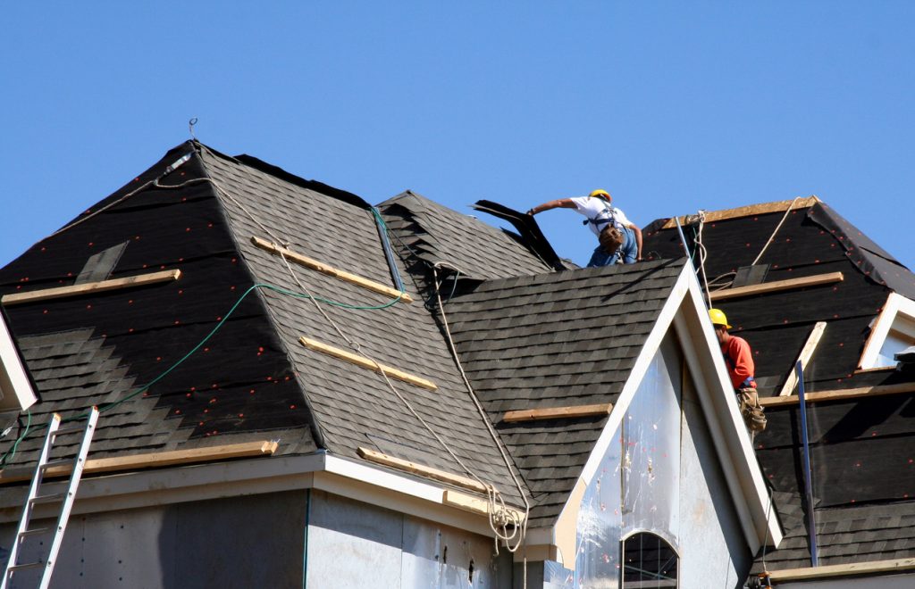 roof workers on top of house with blue sky