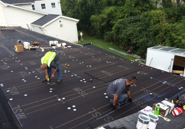 two male workers putting in new roof of building