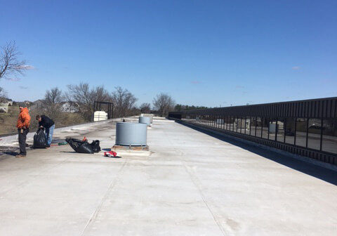 workers repairing flat roof of large building