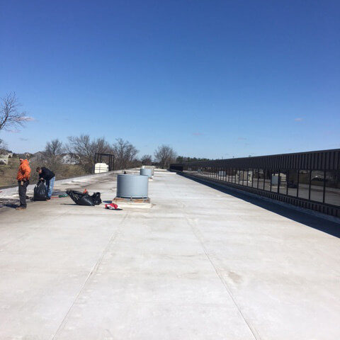 workers repairing flat roof of large building